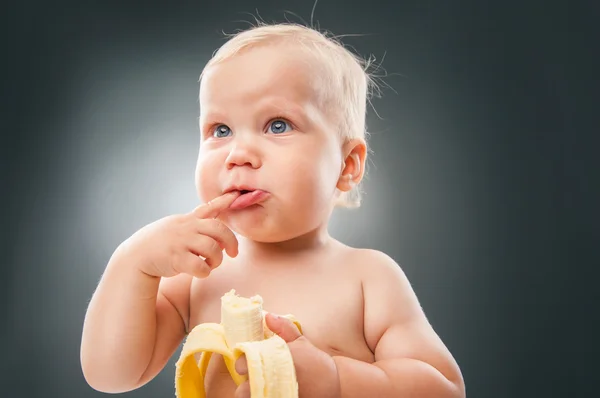 Lustiges Baby macht Gesichter, während es Banane hält — Stockfoto