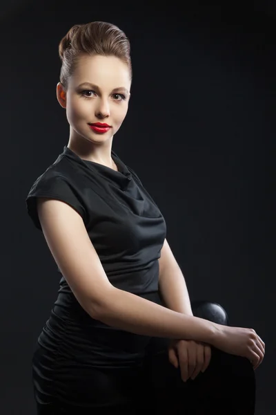 Young elegant woman in black dress near chair — Stock Photo, Image