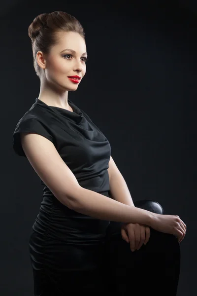 Young elegant woman in black dress near chair — Stock Photo, Image