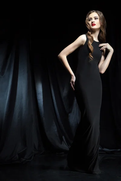 Элегантная женщина в черном платье с руками на бедрах — стоковое фото