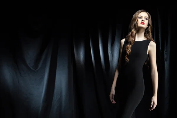 elegant woman with long wavy hair against of black cloth