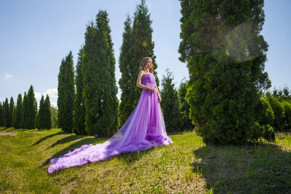 Young woman in beautiful dress amongst trees — Stock Photo, Image