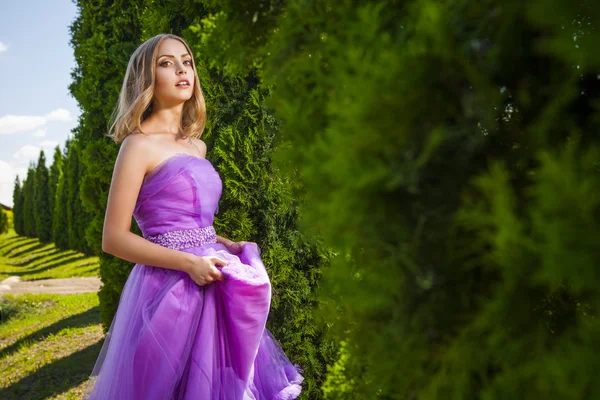 Mooie vrouw in violet jurk camera kijken — Stockfoto