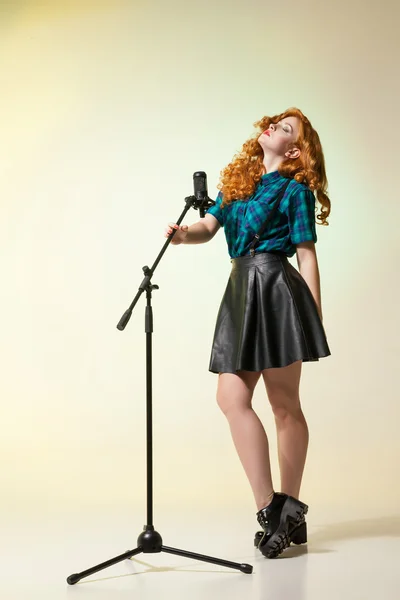 Stylish red-haired woman in leather skirt with suspenders holdin — Stock Photo, Image