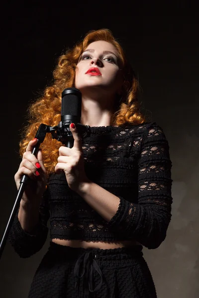 Portrait of curly-haired singer with red lips holding mic — Stock Photo, Image