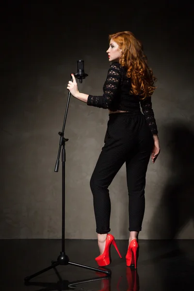 Портрет прекрасной певицы на красных каблуках и черной одежде — стоковое фото