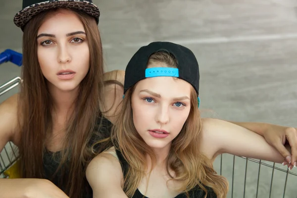 Caucasian girls in cap in cart looking at camera — Stock Photo, Image