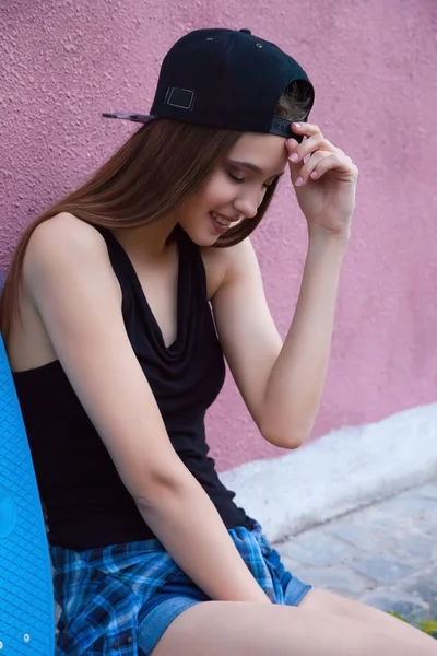 Chica joven con gorra y pantalones cortos sobre la pared rosa — Foto de Stock