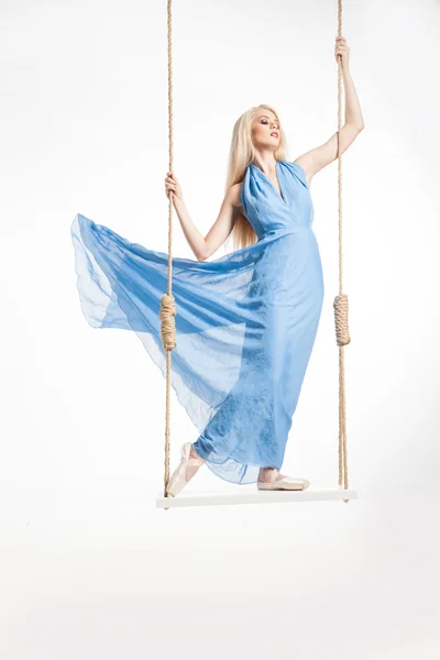 Блондинка в голубом платье на качелях — стоковое фото