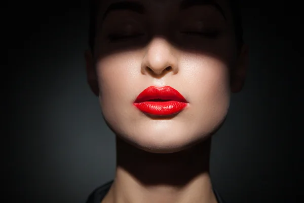 Schönes Modell mit leuchtend roten Lippen und Gesicht, das zur Hälfte von Schatten bedeckt ist — Stockfoto