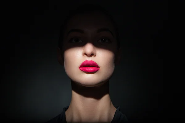 Schönes Modell mit leuchtend rosa Lippen und Gesicht, das zur Hälfte von Schatten bedeckt ist — Stockfoto