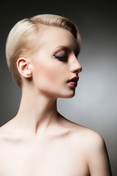 Hermosa joven modelo con maquillaje y peinado mirando hacia abajo — Foto de Stock