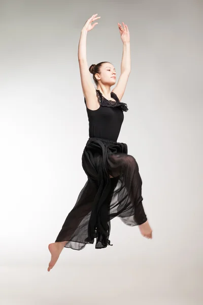 Young ballet dancer wearing black transparent dress jumping — Stock Photo, Image