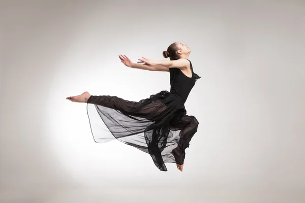 Nuori baletti tanssija yllään musta läpinäkyvä mekko hyppääminen — kuvapankkivalokuva