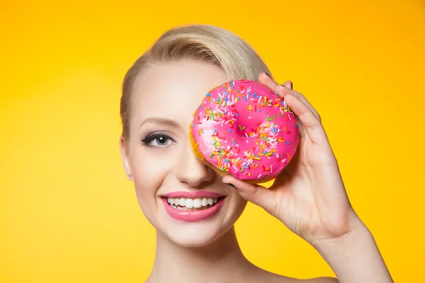 Studio shot van blonde model met donut die betrekking hebben op ogen — Stockfoto