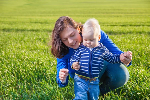 Giovane madre e suo figlio si divertono, giocando sul campo verde — Foto Stock