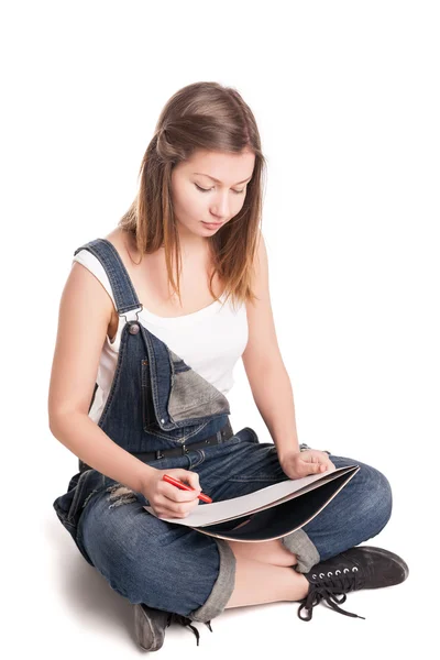 Молода жінка щасливо сидить схрещеними ногами на підлозі малює в її блокноті — стокове фото