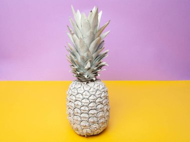 Beyaz ananas stüdyoda, menekşe ve sarı arka planda.