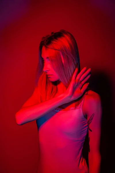 Mulher anônima cobrindo rosto com mão em luz de néon vermelho — Fotografia de Stock