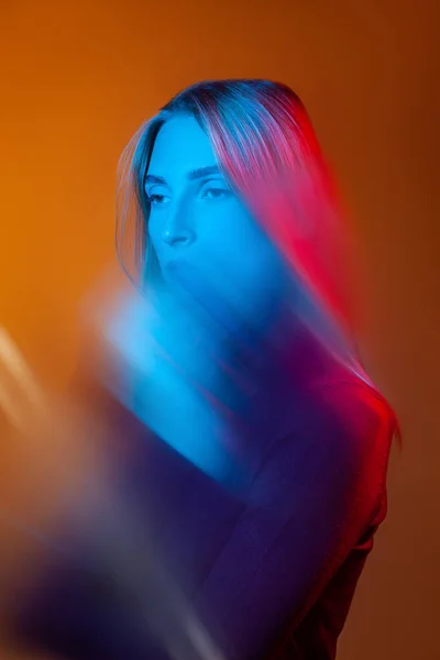 오렌지 스튜디오에서 얼굴에 푸른 빛을 비추는 생각깊은 아가씨 — 스톡 사진