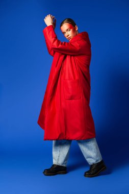 Mavi arka planda parmak uçlarında dans eden moda kadın