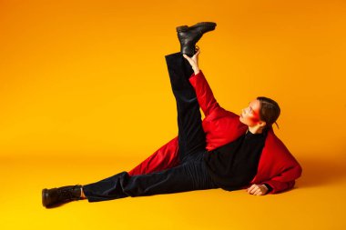 Sarı arka planda uzanan şık bir kadın modeli