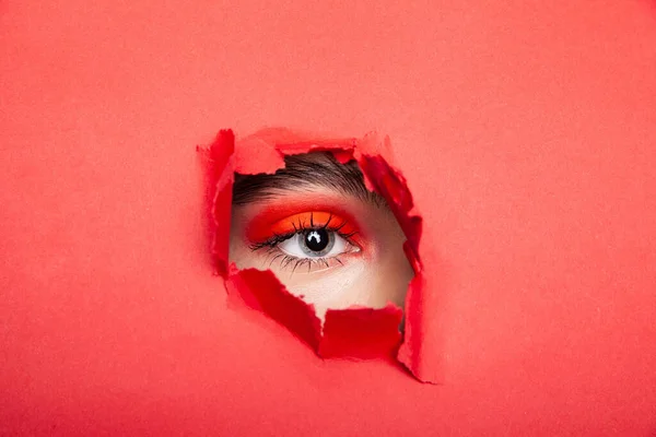 Vrouw op zoek trog rood gescheurd papier in studio — Stockfoto