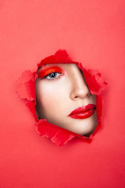 Femme au visage rouge regardant à travers du papier déchiré — Photo