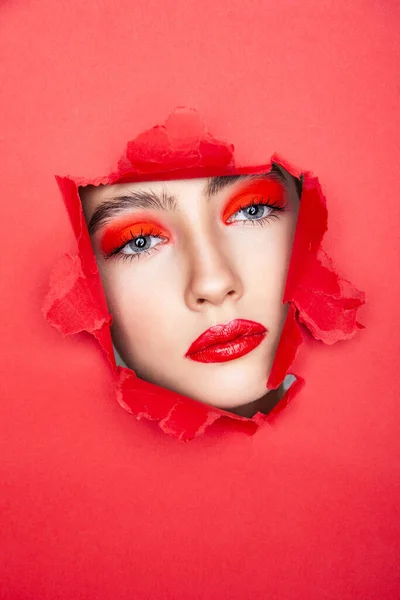 Mujer con rostro rojo mirando a través de papel roto — Foto de Stock