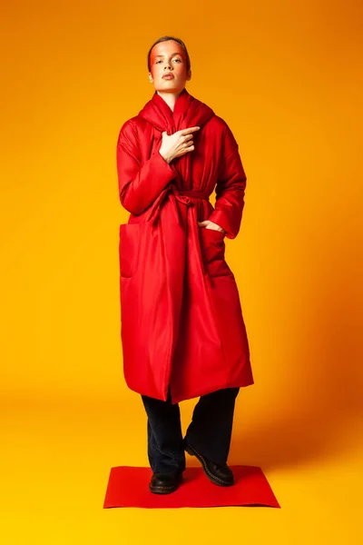 Жіноча модель в модному червоному пальто на жовтому тлі — стокове фото