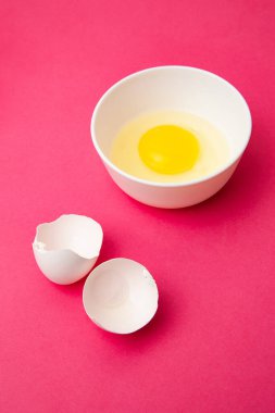 Pembe yüzeyde, kabuğun yanında kırık yumurta var.