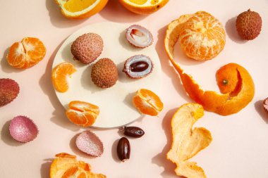 Pembe masaya dizilmiş lezzetli liçi ve portakallar.