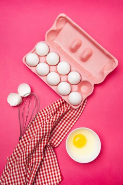 Yumurta kutusu yumurta sarısı kasesinin yanında ve pembe masada çırpın.