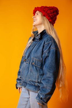 Parlak turuncu arka planda kalın giysili neşeli hippi kadın.