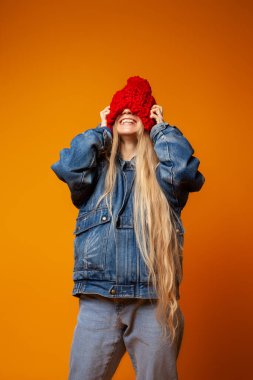 Kırmızı örgü şapkalı hippi kadın turuncu arka planda.