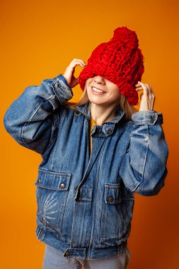 Kırmızı örgü şapkalı hippi kadın turuncu arka planda.