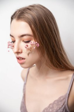 İç çamaşırlı, yüzünde çiçekler olan nazik genç bir kadın.