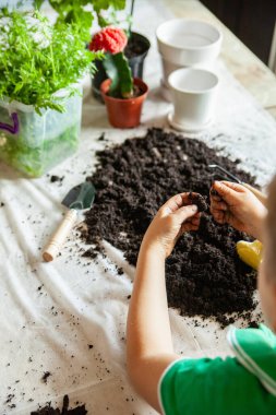 Tırmıklı çocuk masada toprakla oynuyor.