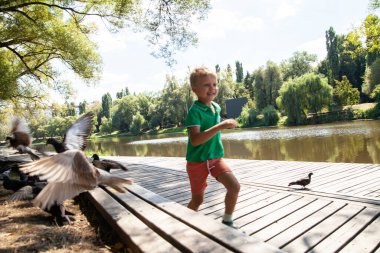 Küçük çocuk yaz günü tahta yolda koşuyor.