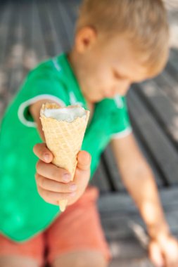 Parkta dondurma külahı gösteren neşeli çocuk.