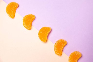 Renkli arkaplanda köşegen sırasına dizilmiş meyveli jöle şekerleri