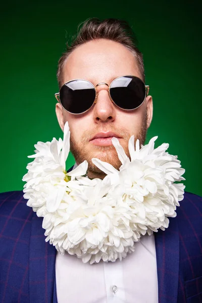 Serieuze man in pak en met bloemen in baard op zoek naar camera — Stockfoto