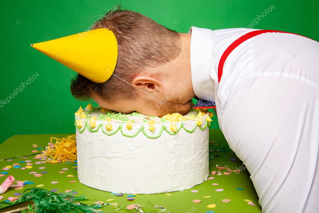 Funny man lying with face in birthday cake