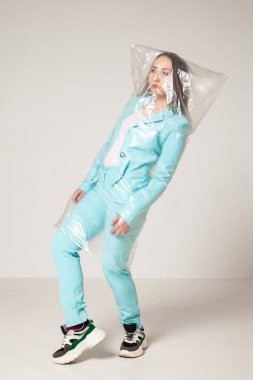 Gri arka planda plastik çantalı şık bir kadın