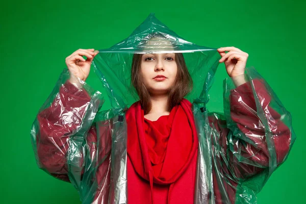 Stüdyoda yeşil arka planda duran yağmurluklu kadın. — Stok fotoğraf