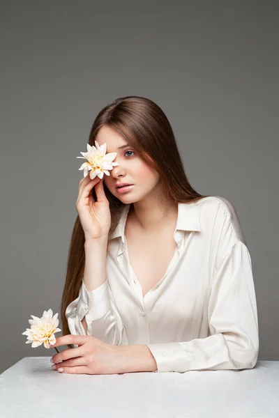 Mujer joven cubriendo el ojo con flor fresca — Foto de Stock