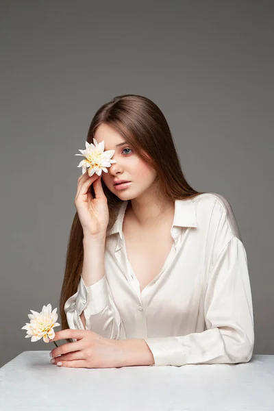 Young woman covering eye with fresh flower — Zdjęcie stockowe