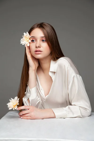 Mujer joven cubriendo el ojo con flor fresca — Foto de Stock