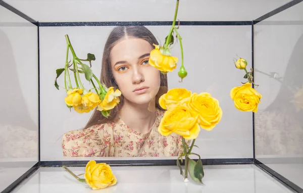 Female model behind glass box with flowers — Stockfoto