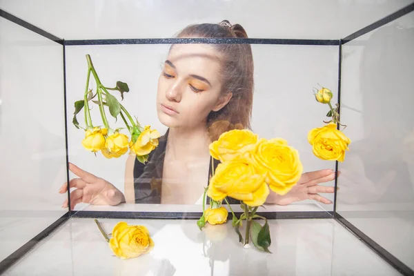 Женская модель за стеклянной коробкой с цветами — стоковое фото
